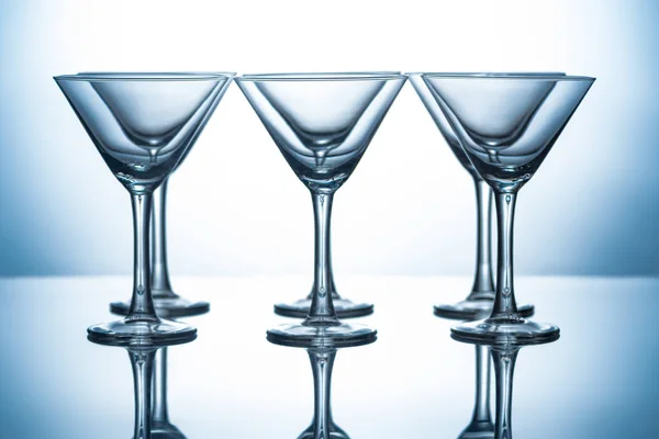 Reihe Transparenter Martini Gläser Auf Grau Mit Reflexen — kostenloses Stockfoto