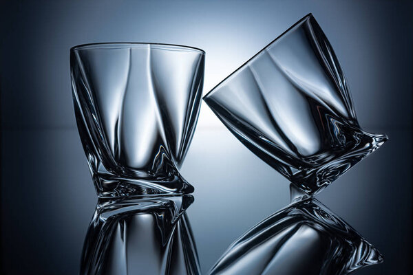 two transparent empty cognac glasses on grey with reflections