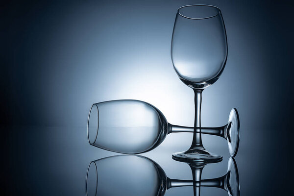 silhouettes of empty wineglasses with reflections, on grey