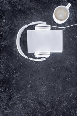 top view of white book, headphones and cup of coffee with milk on grey tabletop clipart