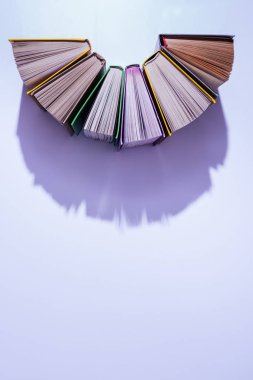 top view of stack of books in half circle on violet table clipart