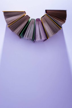 menekşe masada yarım daire içinde kitap yığını yükseltilmiş görünümünü