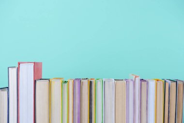 row of different colored books isolated on blue