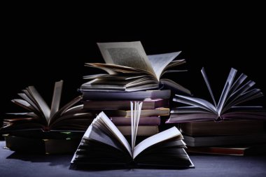 stack of books on dark surface on black clipart