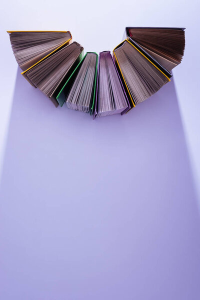 elevated view of stack of books in half circle on violet table