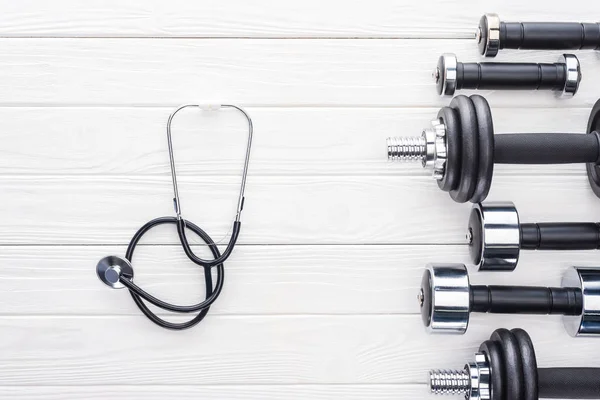 Top View Various Dumbbells Stethoscope White Wooden Surface — Stock Photo, Image