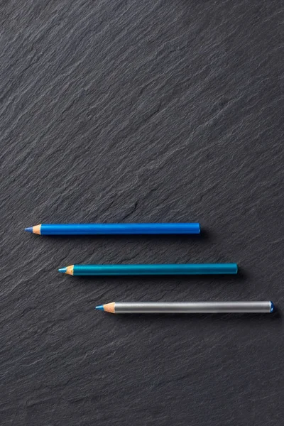 黑色石板背景上蓝色色调的化妆铅笔 — 图库照片
