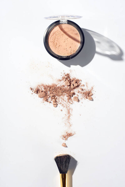 Brush and beige face powder on white background