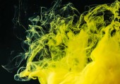 close-up view of bright yellow flowing paint on black background