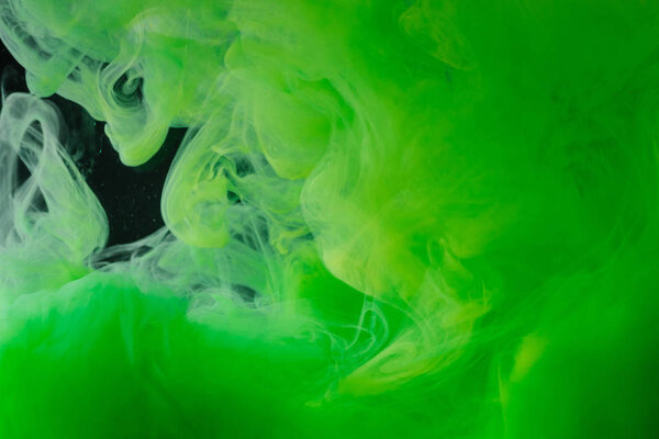 close-up view of bright green abstract flowing ink on black background   