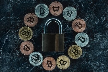 karanlık mermer yüzeyindeki görücü usulü kilit ve çeşitli bitcoins üstten görünüm
