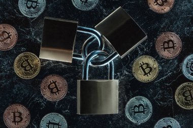 karanlık mermer yüzeyindeki görücü usulü kilitler ve çeşitli bitcoins üstten görünüm