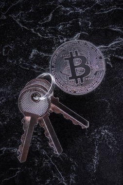 karanlık mermer masa üzerinde ayarlanmış anahtarlar ve gümüş bitcoin üstten görünüm