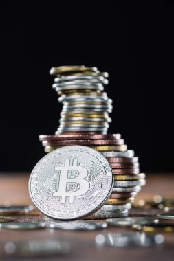 selective focus of silver bitcoin and piles of bitcoins behind clipart