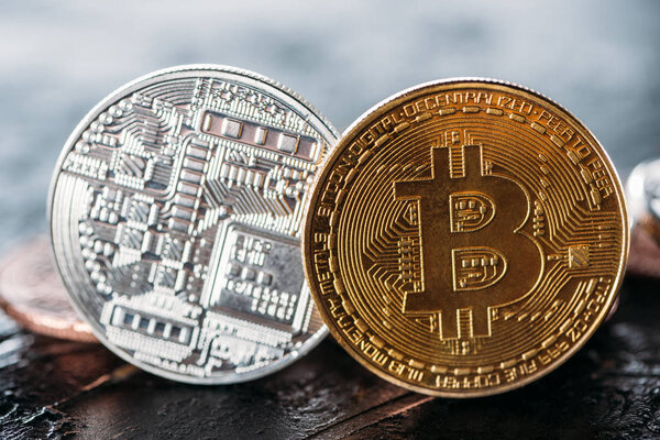 close up view of golden and silver bitcoins on dark surface