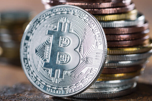 селективный фокус биткойна серебра и кучи биткойнов позади
