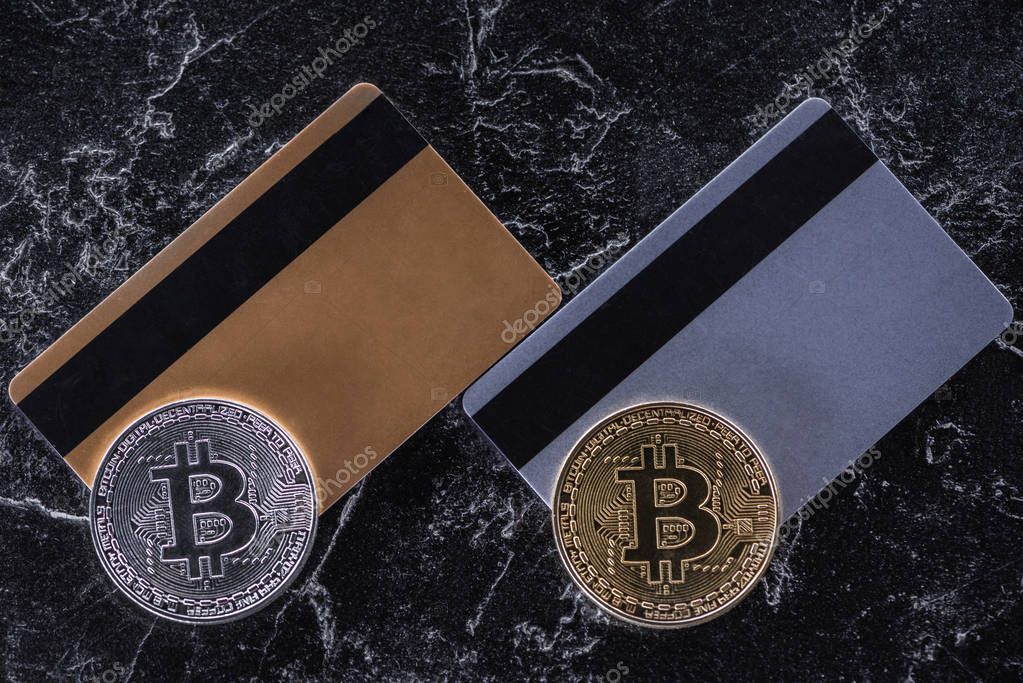 Top view of credit cards and bitcoins on dark marble surface