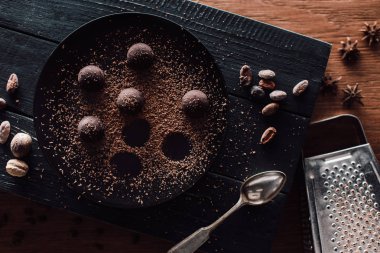 kesme tahtası yer mantarı ile üstten görünüm tabakta rendelenmiş çikolata anason, kaşık, kakao çekirdekleri, nutmegs ve rende ahşap masa üzerinde kapsayan