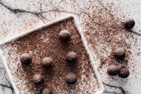 top view of plate with truffles covering by grated chocolate on marble table 