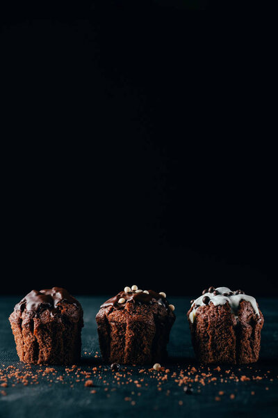 Delicious muffins with glaze on dark background
