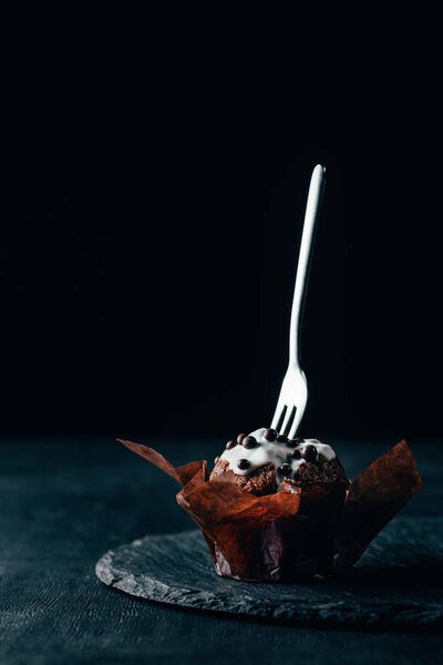Sweet chocolate muffin with silver fork on dark background