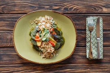 Çatal üstten görünüm üzerinde ahşap masa üzerine rendelenmiş badem peçete ve vejetaryen salatası