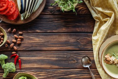 flat lay with arranged fresh vegetables and vegetarian cream soup on wooden tabletop clipart