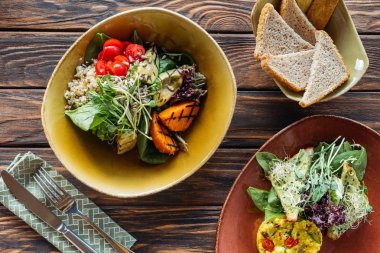 kase, ekmek ve çatal bıçak takımı ahşap masa üzerinde düz lay vejetaryen salata ile servis