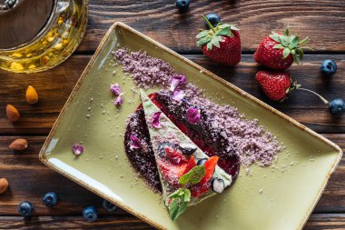 Düzenlenmiş vejetaryen tatlı çilek ile üstten görünüm plaka, badem ve ahşap yüzeyde çaydanlık