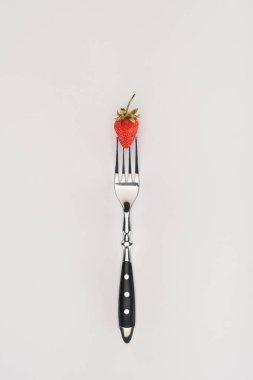 Raw strawberry on a fork isolated on white background clipart