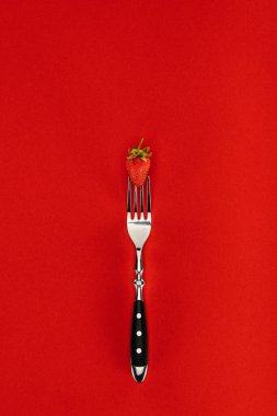 Red strawberry on a fork isolated on red background clipart