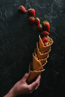 Gözleme koniler yaz çilek ile koyu arka plan üzerinde tutan el