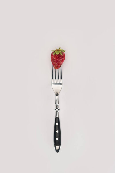 Red strawberry on a fork isolated on white background