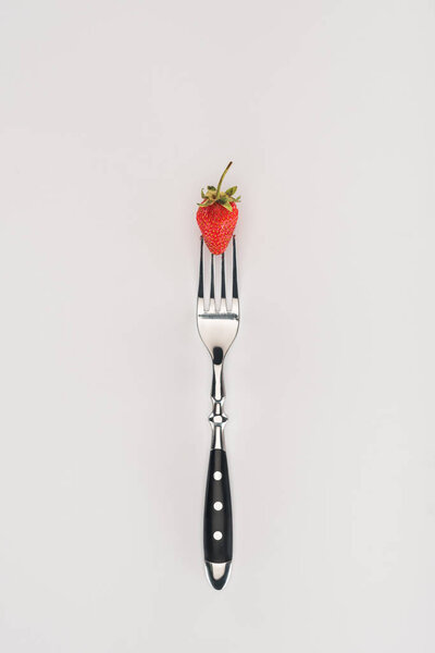 Raw strawberry on a fork isolated on white background