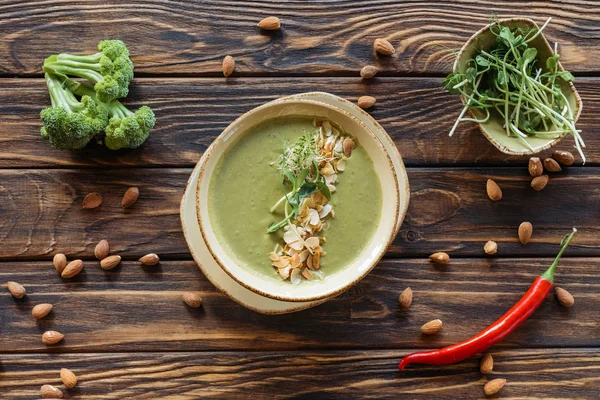 Top view of arranged vegetarian cream soup, fresh broccoli, almonds and chili peppers on wooden surface — Stock Image Top View Arranged Vegetarian Cream Soup Fresh Broccoli Almonds Chili Stock Picture