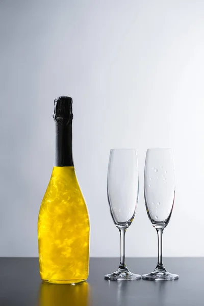 关闭在灰色背景下的香槟瓶和空眼镜的视图 — 免费的图库照片