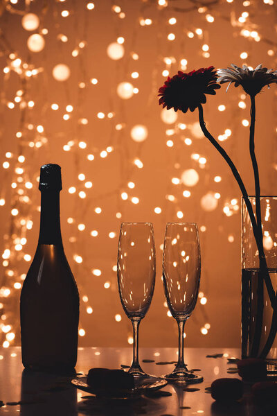 close up view of bottle of champagne, empty glasses and bouquet of flowers on tabletop