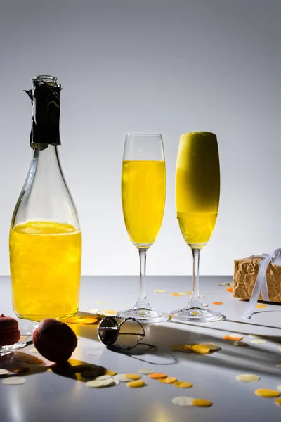 灰色の背景に黄色のシャンパン ギフトにガラスのビューをクローズ アップ  — 無料ストックフォト