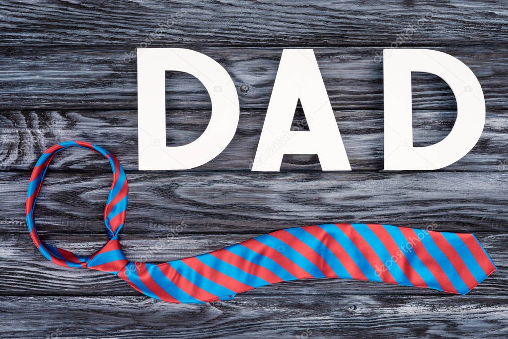 top view of tie with DAD lettering on grey wooden surface, Happy fathers day concept
