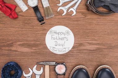 top view of Happy father's day greeting card surrounded with fathers attribution on wooden surface clipart