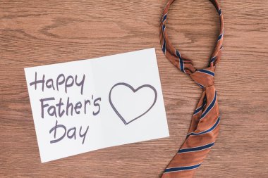 top view of tie with Happy fathers day greeting card on wooden surface clipart