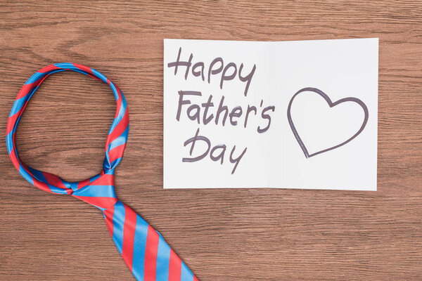 top view of vivid tie with Happy fathers day greeting card on wooden surface
