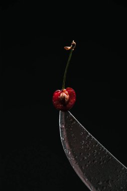 close-up view of half of ripe sweet cherry on knife isolated on black  clipart