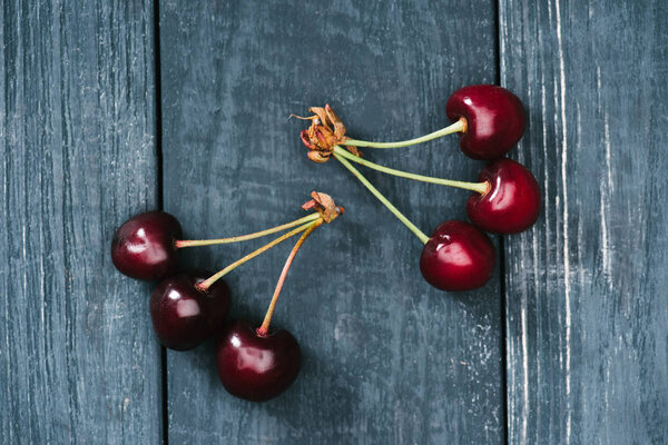 top view of ripe sweet cherries on rustic wooden surface