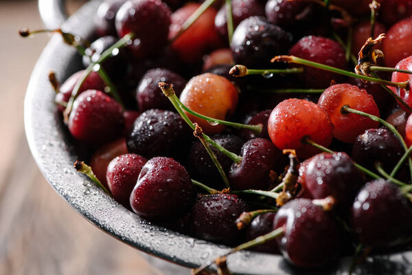 close-up view of fresh sweet organic cherries with water drops in colander