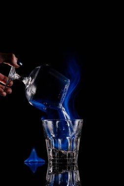 siyah arka plan üzerine yanan sambuca alkol içki cam içine dökme kadının kısmi görünümü