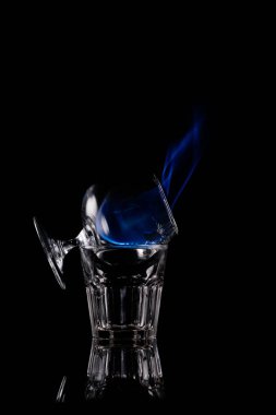 close up view of alcohol sambuca drink burning in glass on black background clipart