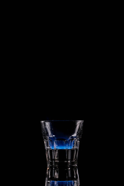 close up view of alcohol sambuca drink burning in glass on black background