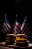 tasty burgers on wooden cutting board in front of small united states flags