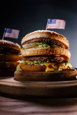 Siyah ahşap kesme tahtası üzerinde ABD bayrağı ile lezzetli hamburger yakın çekim çekim pimleri